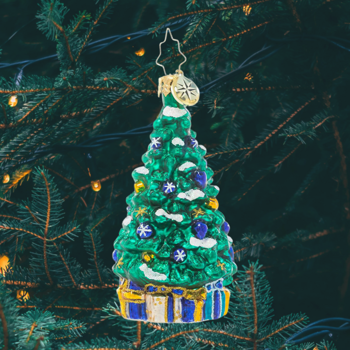 Ornament Description - Shimmering In Sapphire Gem: This stylish tree is trimmed and ready for the big night, eschewing traditional red for a more subdued blue, white and gold. Presents tucked beneath the branches match the calm tones of the ornaments perfectly, completing the sophisticated look!