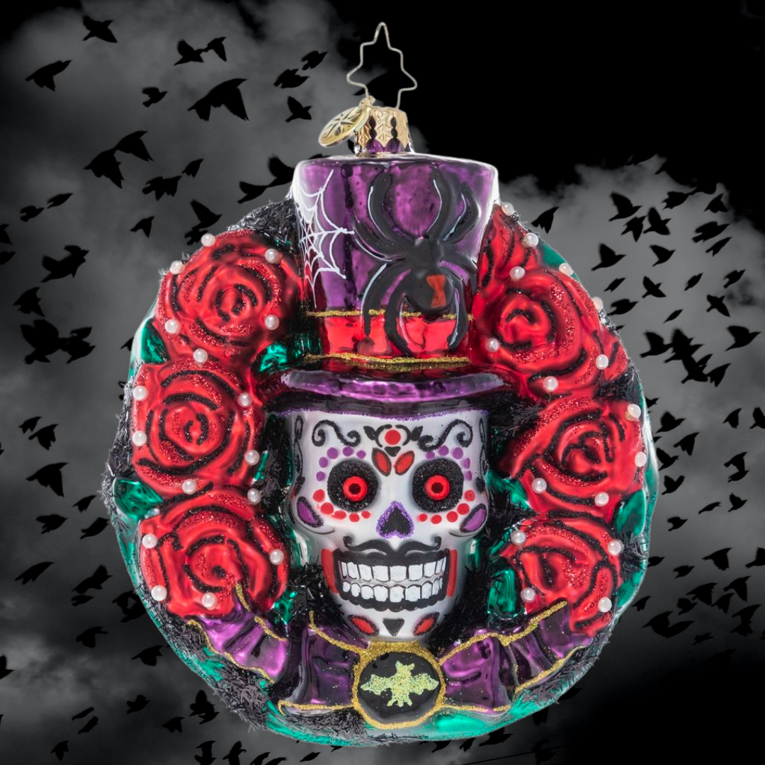 Ornament Description - Spooky Skull Wreath: Celebrate spooky season with this gothic-inspired calavera wreath. A ring of blood-red roses encircles a trio of black bats and a grimacing sugar skull – all things that make Halloween so frightfully fun!