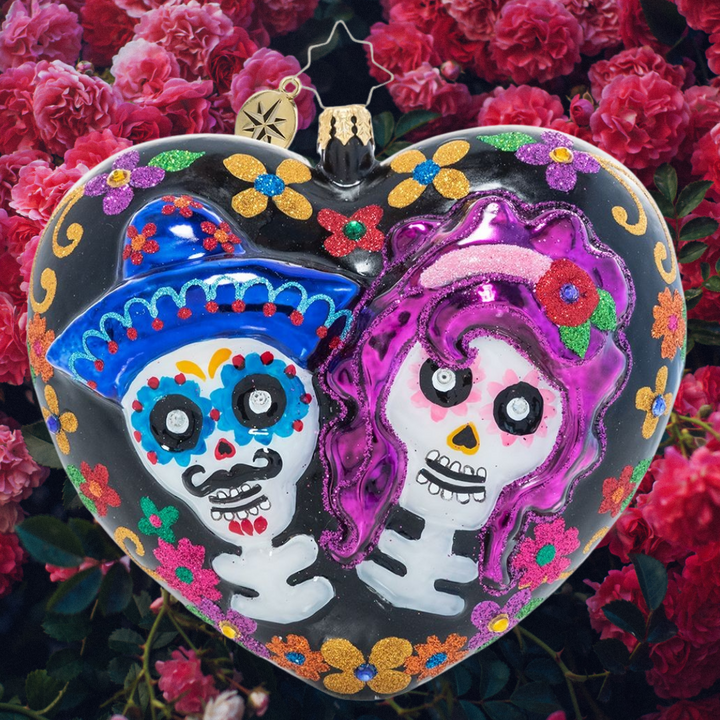 Ornament Description - Sugar Skull Sweethearts: Remember those we've lost and celebrate love and life with this brightly colored heart-shaped ornament. Beautiful stylized flowers adorn one side while two sugar skull lovers wink out from the other on this Día de los Muertos-inspired ornament.