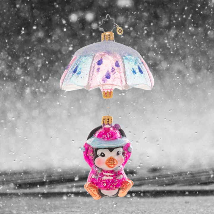 Ornament Description - When It Rains It Pours: Look out below! This adorable penguin pal is drifting in with the snowfall on a pastel parasol.