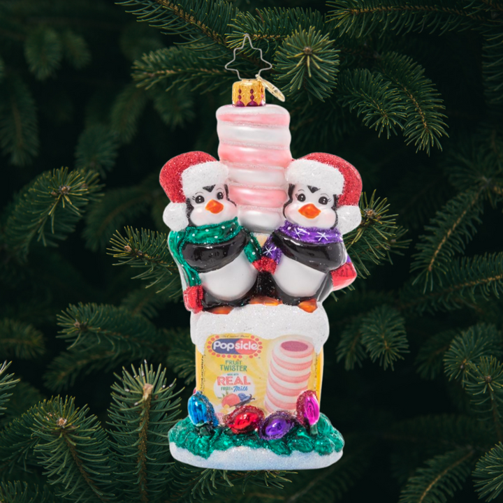 Ornament Description - Popsicle Penguin Pals: Brrr! This pair of penguin pals is truly in their element atop a frosty box of Popsicle frozen treats. After all, they take "chilling" with friends very seriously at the North Pole!