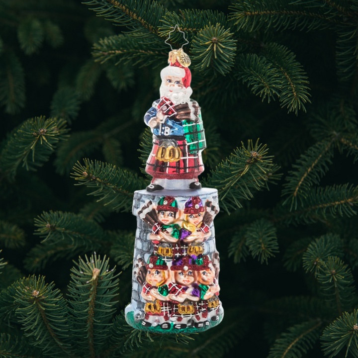 Ornament Description - Piper Posse: The penultimate addition to our Ornament of the Month series, this piece celebrates the 11th day of Christmas. You can practically hear the music coming from this team of tiny bagpipers led by their eleventh member and Christmas king himself, Santa Claus!