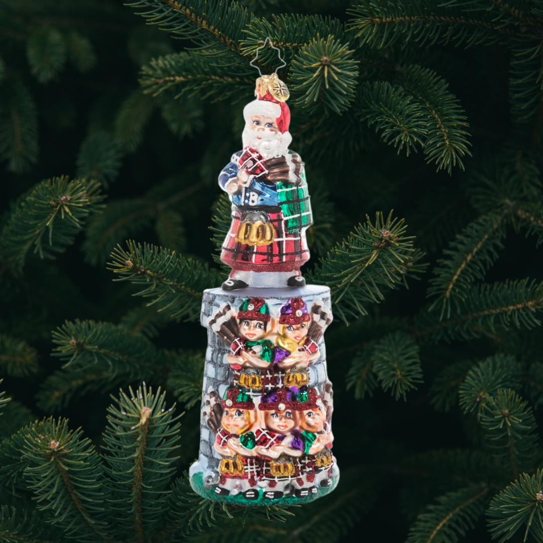 Ornament Description - Piper Posse: The penultimate addition to our Ornament of the Month series, this piece celebrates the 11th day of Christmas. You can practically hear the music coming from this team of tiny bagpipers led by their eleventh member and Christmas king himself, Santa Claus!