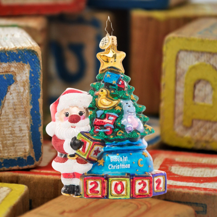 Ornament Description - Extra Special Delivery: This adorable Santa has taken extra special care of the latest addition to his nice list – a new baby in the family! Celebrate their first Christmas with this darling ornament featuring a tiny tree decorated with special treasures to delight any little one.