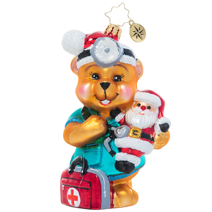 Front - Ornament Description - The Doctor is In: Dr. Teddy is ready to see (and snuggle!) some patients! He believes that love is the best medicine and wants to share encouragement and cheer with the sick children who need him most. A percentage of the sales from this ornament will benefit Pediatric Cancer charities.