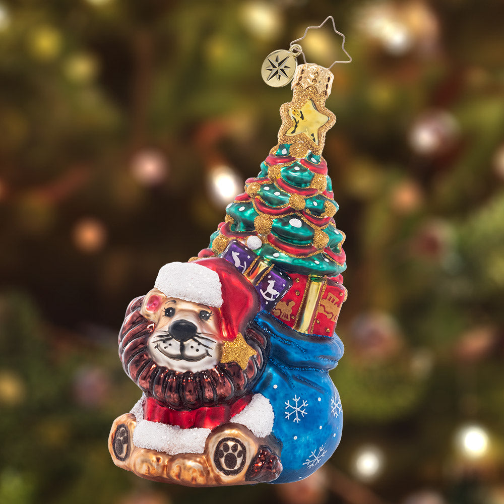Ornament Description - Cub's First Christmas: This brave little lion cub has a bag full of fun trailing behind him, ready to make baby's first Christmas extra special!