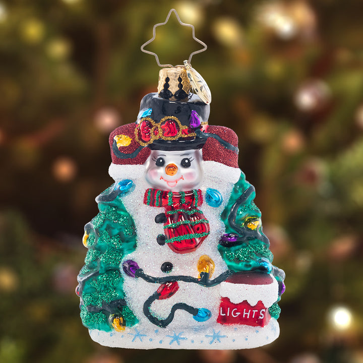 Ornament Description - Let There Be Lights Gem: Success! This sweet little snowman finally untangled the Christmas lights, so he's ready to deck the halls with holiday cheer.