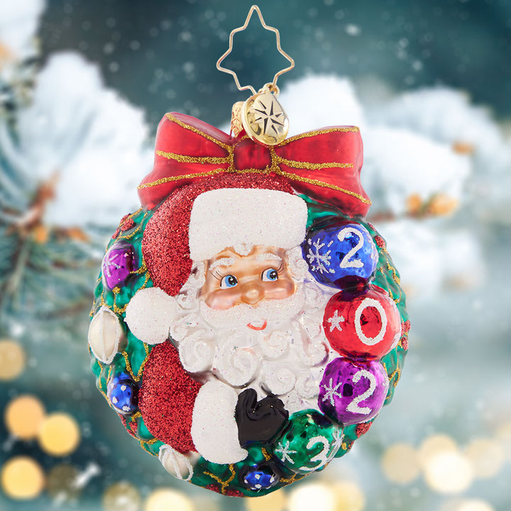Ornament Description - Smiling Through 2023 Gem: Perfectly perched within a wintry wreath, Santa celebrates 2023 with gorgeous, glistening ornaments.