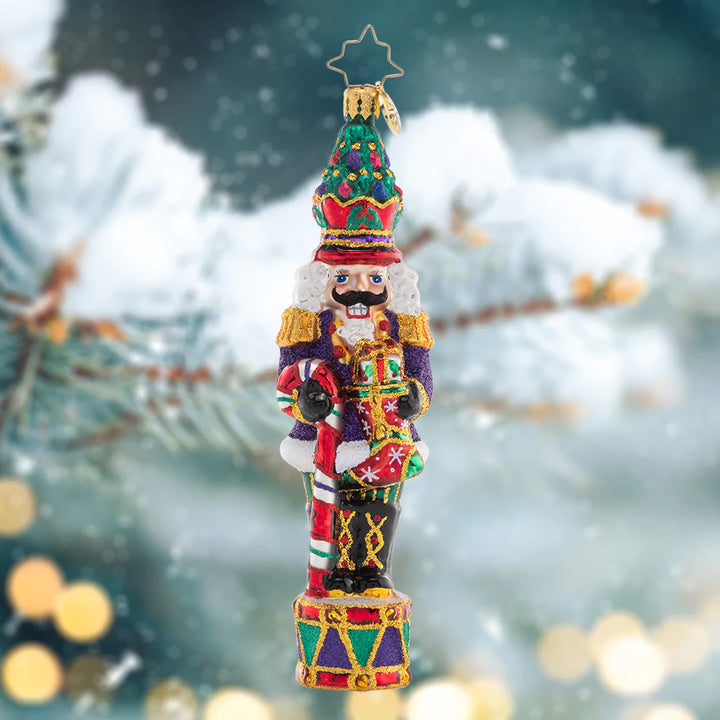 Ornament Description - Christmas Commander Nutcracker: Complete with a Christmas tree crown, this nutcracker is truly a commanding presence! He's ready to make this holiday the best one yet with a candy cane staff and plenty of gifts.