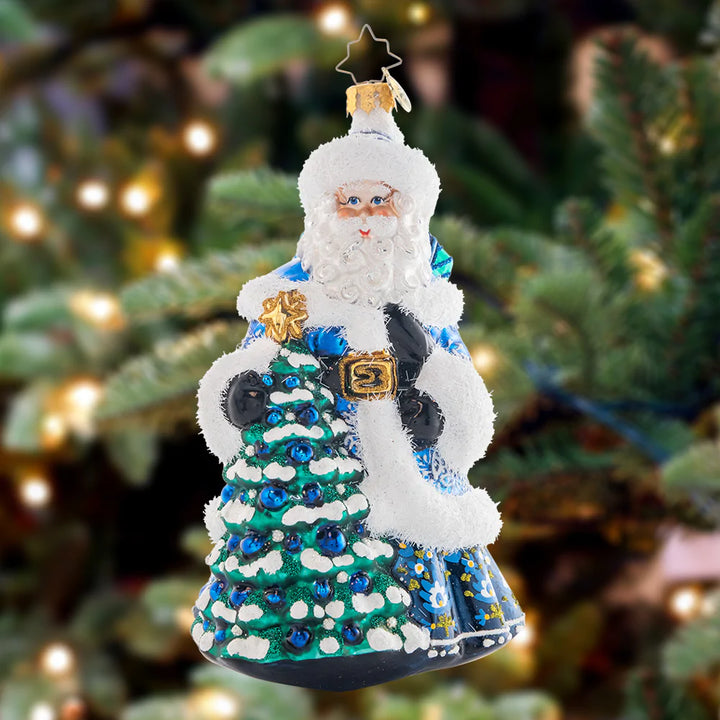 Ornament Description - Winter Hues Santa: Dressed from head-to-toe in cool winter blues, Santa totes a splendid giftsack embellished with intricate snowflakes. Even his noble fir tree is trimmed in blue!