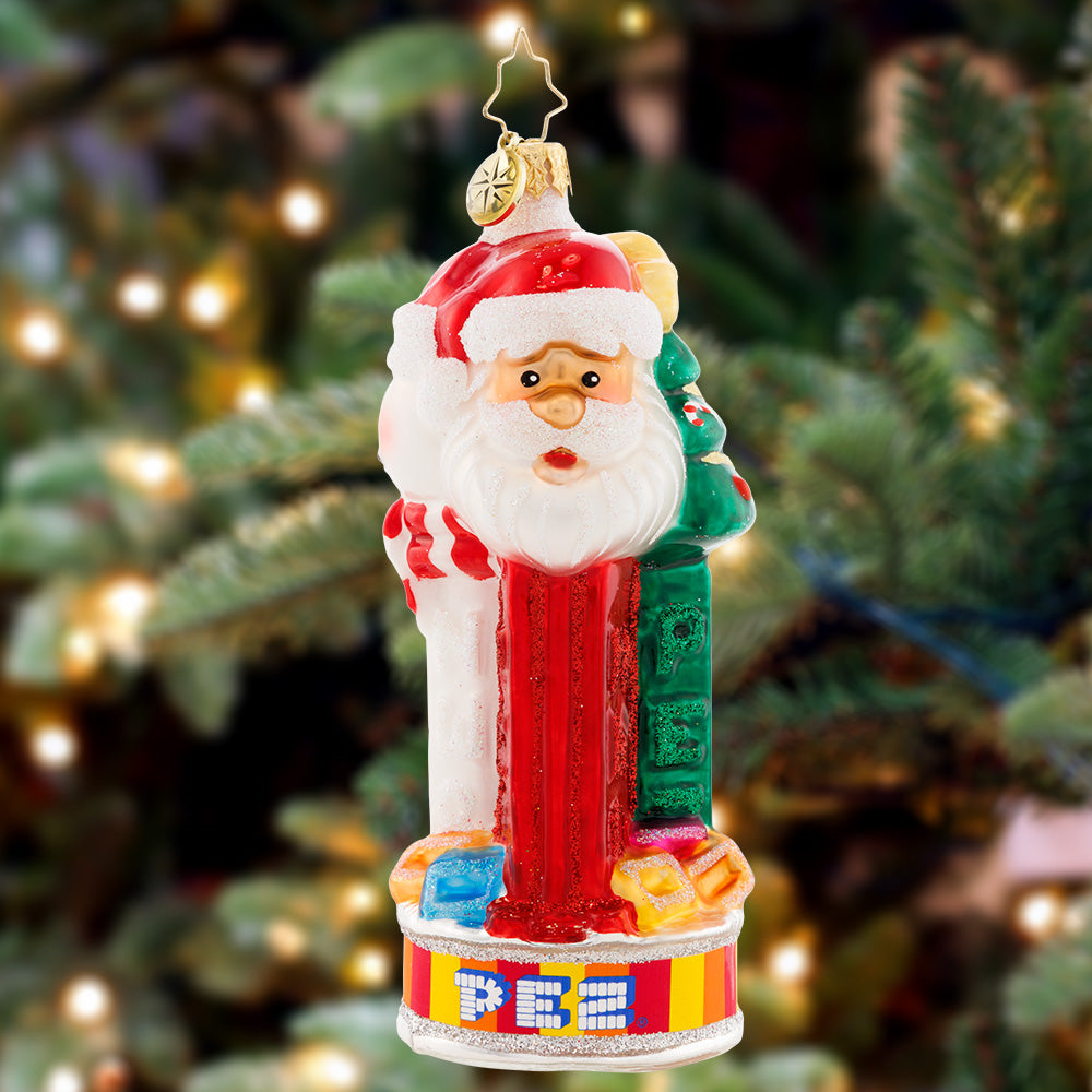 Ornament Description - Jolly PEZ™: Bring iconic cheer to your holiday décor with this festive display of PEZ™ Candy dispensers. Three PEZ™ dispensers of Tannenbaum, Snowman and Santa Claus characters all atop the colorful trademark candy wrapper base.