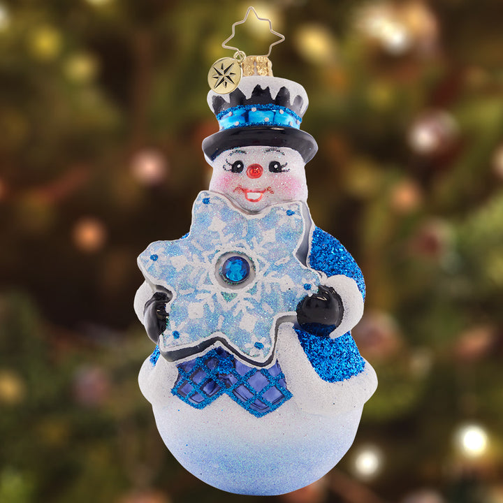 Ornament Description - Flakey Frosty: Showing off his stunning star-shaped snowflake, this frosty friend is a vibrant vision in blue.
