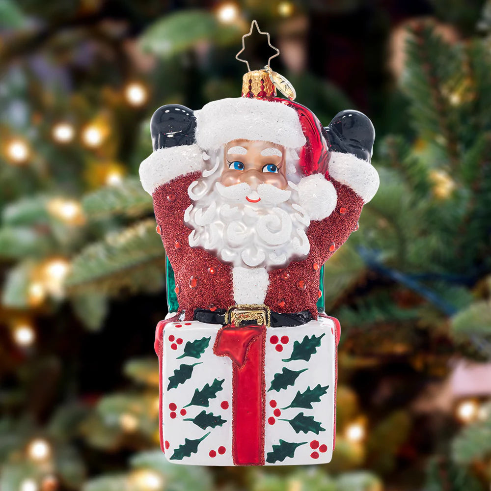 Ornament Description - Santa-In-The-Box: Pop-goes-the-Santa! This jolly fellow is the most wonderful Christmas surprise, popping out of a holly-decked gift box.