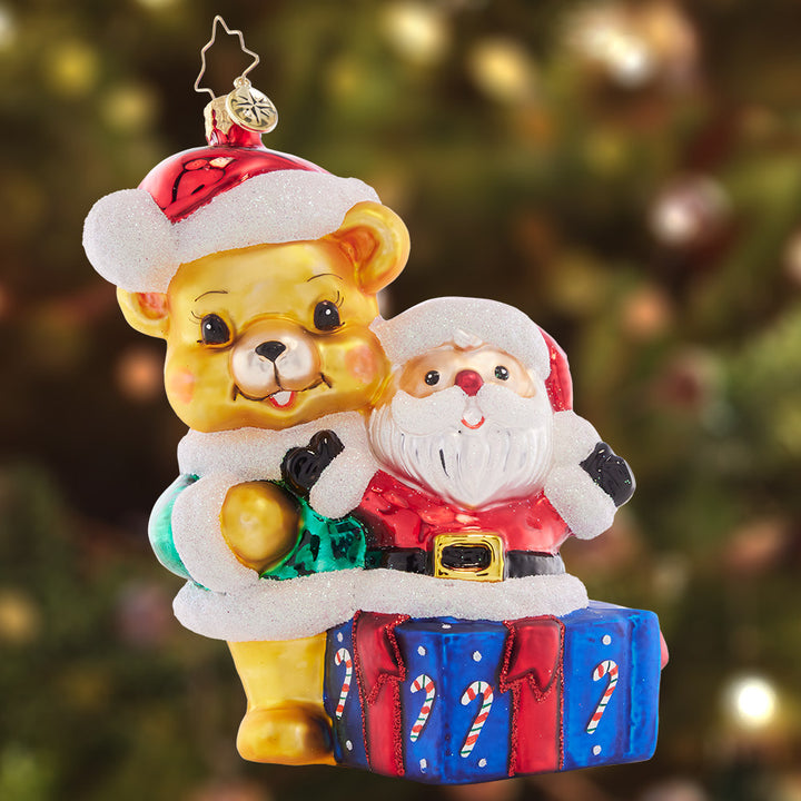 Ornament Description - Present For Ted E. Bear: Surprise! This sweet teddy bear presents the perfect Christmas gift – a jolly Santa Claus filled with holiday cheer.