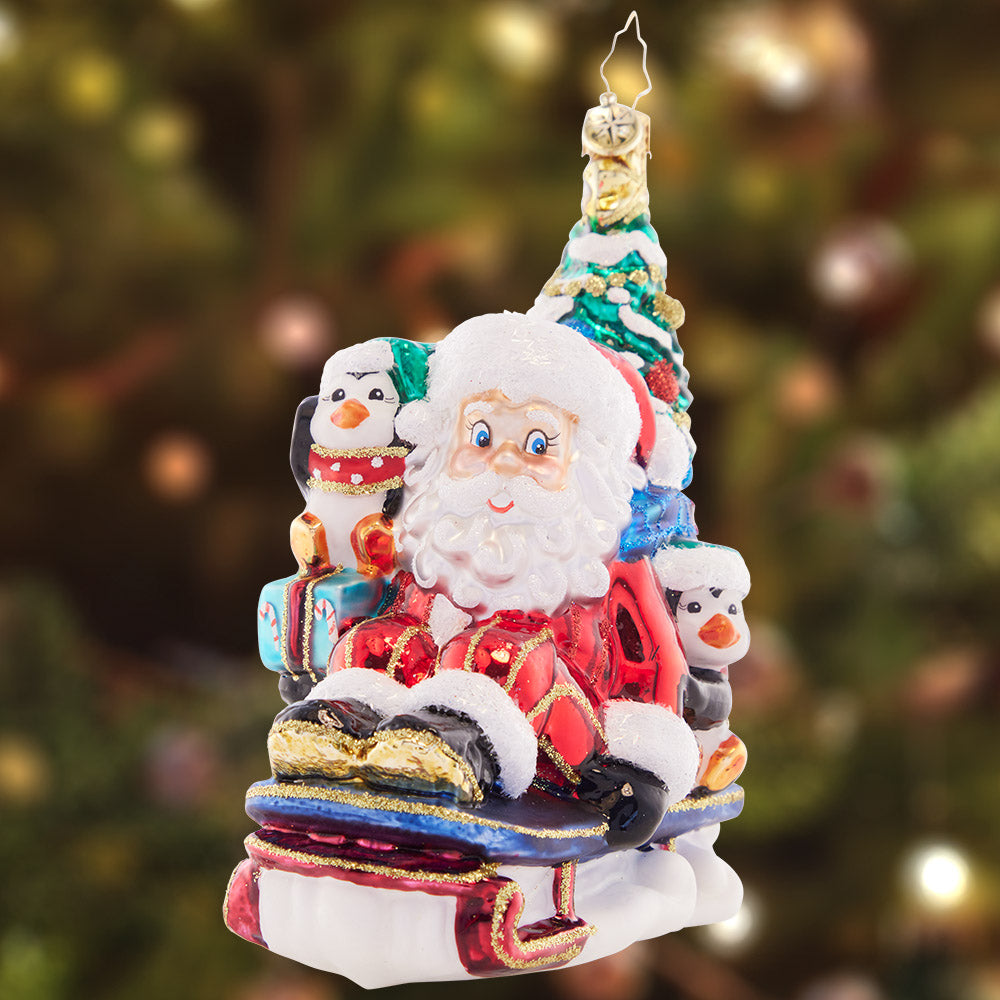 Ornament Description - Christmas Getaway: Perfectly prepared with a trimmed tree, a sack of presents, and his trusty penguin pal, Santa zooms by in his speedy sled. He's got everything he needs for a cheer-filled Christmas!