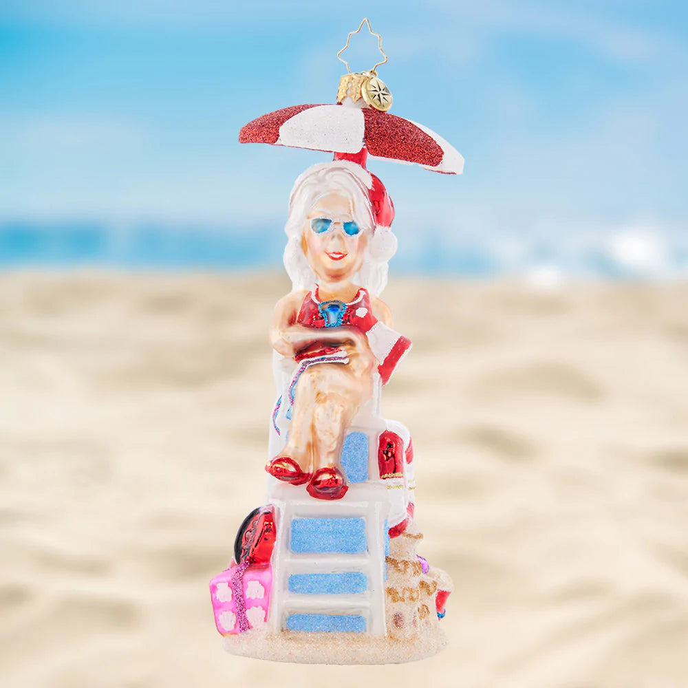 Ornament Description - Lovely Lifeguard: Staying cool under a parasol in her stylish shades, Mrs. Claus is keeping a close eye on the crashing waves.