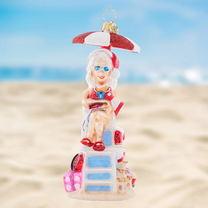 Ornament Description - Lovely Lifeguard: Staying cool under a parasol in her stylish shades, Mrs. Claus is keeping a close eye on the crashing waves.