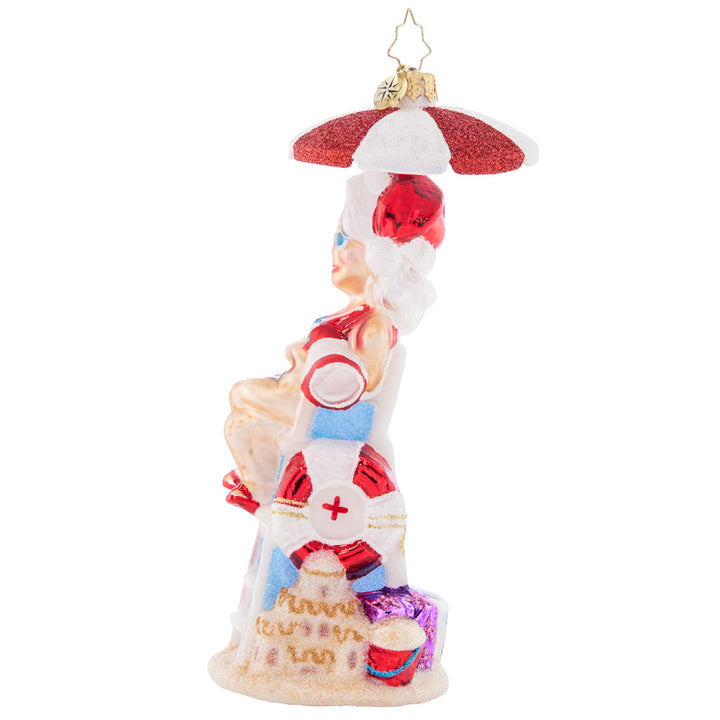 Side View- Ornament Description - Lovely Lifeguard: Staying cool under a parasol in her stylish shades, Mrs. Claus is keeping a close eye on the crashing waves.