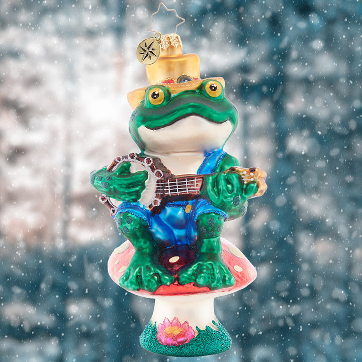 Ornament Description - Bayou Banjo Blues: Perched atop a mushroom as his stage, this fun frog gives his audience a bravo-worthy banjo performance on the bayou.