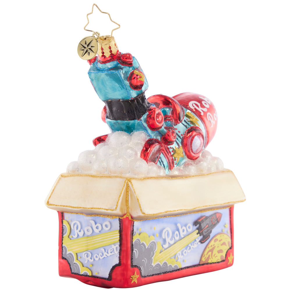 Back-Side View - Ornament Description - Robo Rocket Rides Again: Bursting from the box, this red robo-rocket toy is just begging to be played with on Christmas morning! This ornament evokes nostalgic memories of the of childhood holiday gifts.