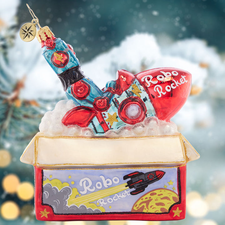 Ornament Description - Robo Rocket Rides Again: Bursting from the box, this red robo-rocket toy is just begging to be played with on Christmas morning! This ornament evokes nostalgic memories of the of childhood holiday gifts.