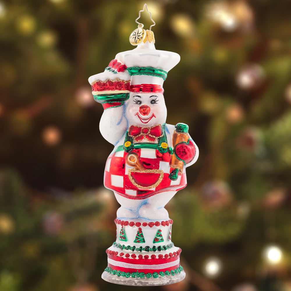 Ornament Description - Cutie Pie Baker: This darling snow pal is the greatest cake maker. She uses cool icicle frosting so these baked goods are never defrosting. Join in the feast of this delicious sweet treat!