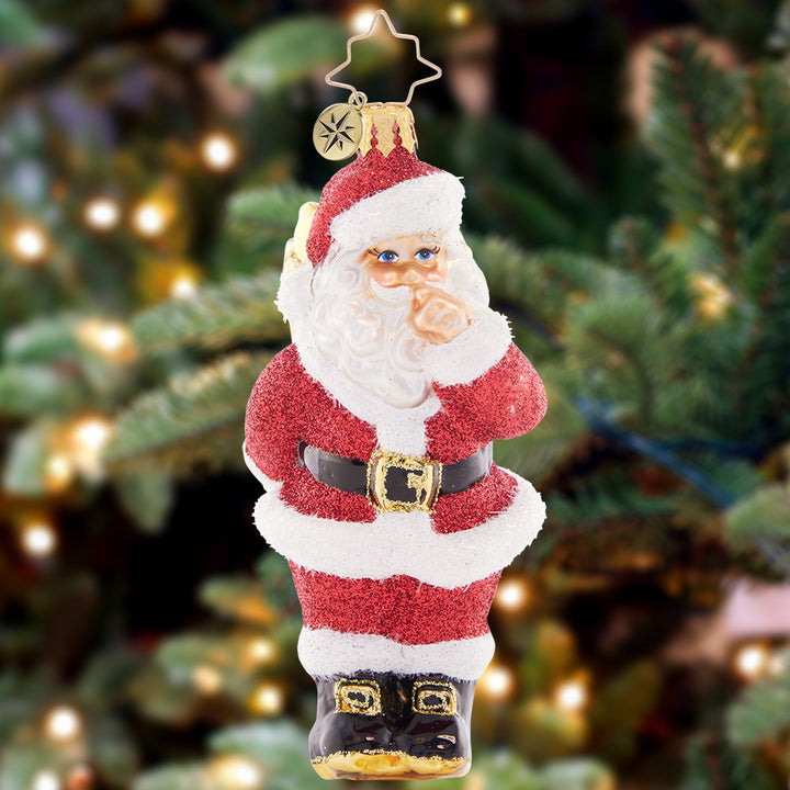 Ornament Description - Santa's Big Surprise: Looks like Santa has a secret – a glorious green gift hidden behind his back! He's ready to share the Christmas cheer by presenting this well-packed parcel.