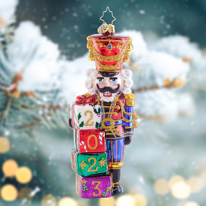 Ornament Description - Crackin' Good Year: This splendid soldier is ready to get cracking on opening Christmas gifts! With a pile of presents adorned with the new year, this dated ornament will be cherished and dear.