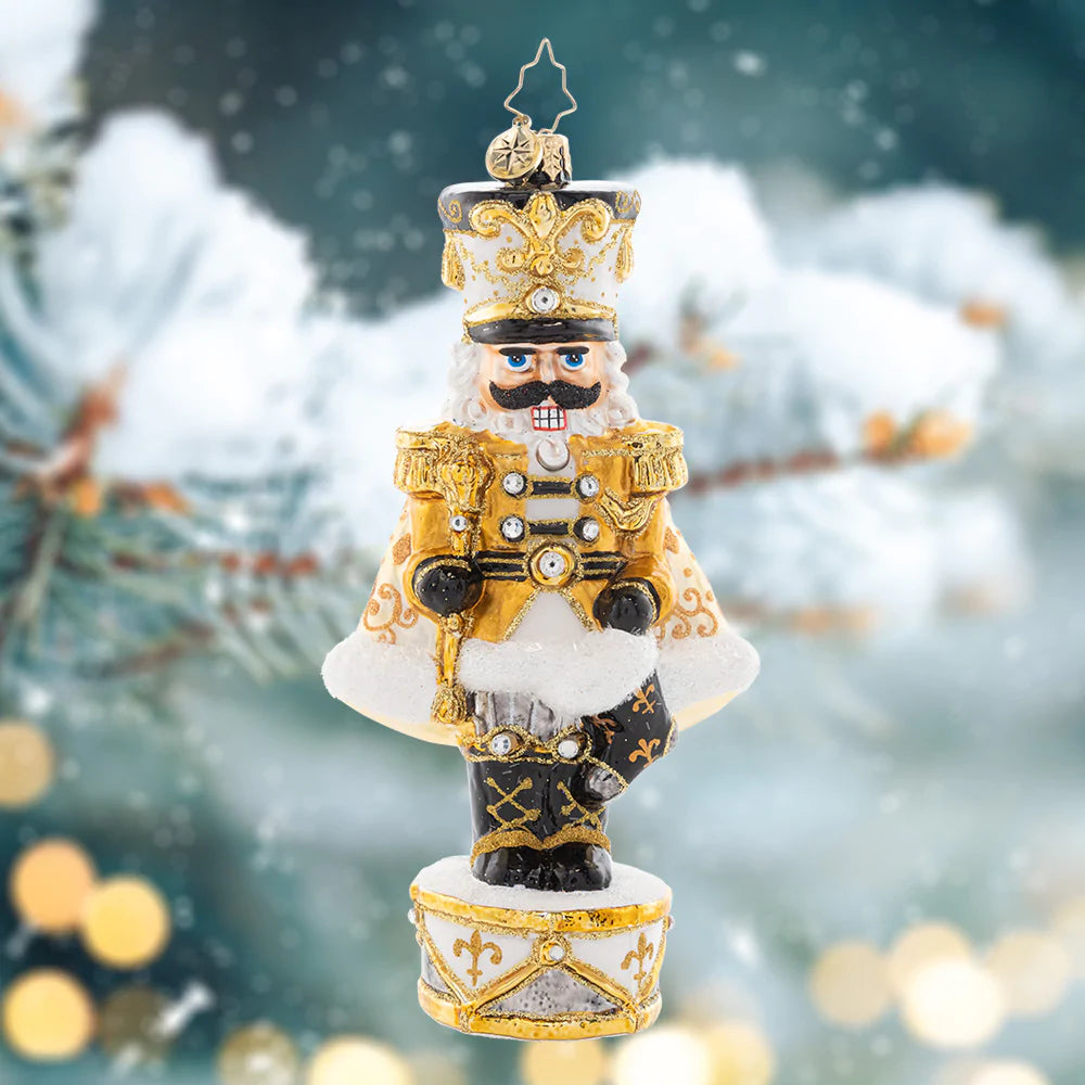 Ornament Description - Golden Guardian: Gleaming and bold in white and gold, this Nutcracker is guarding the gift of Noel. Decorate your tree with this superbly stunning piece.