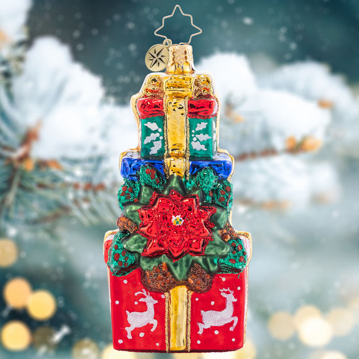Ornament Description - Poinsettia Presents: Perched atop this perfect pile of gifts is a pretty Poinsettia plant! Add a pop of crimson color to your tree with this beautiful ornament.