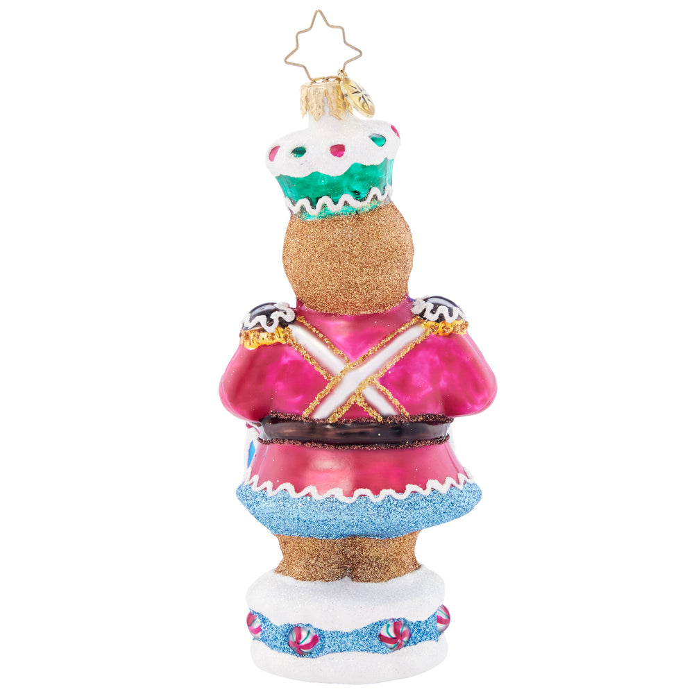 Back - Ornament Description - Drumroll Please: A gingerbread guard gallantly protects the candy castle, ensuring that it outlasts hungry hands of good little girls and boys before Christmas day.
