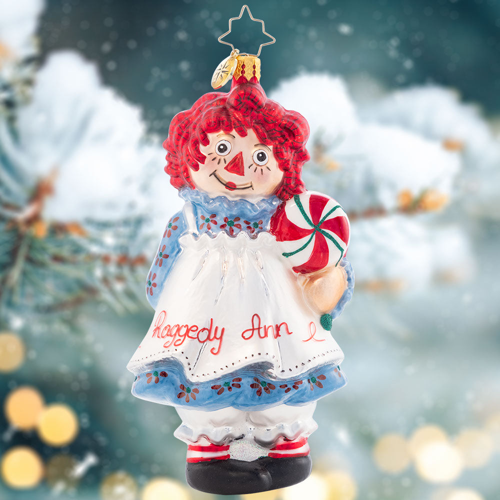 Ornament Description - Raggedy Sweets: This timeless sweetie has her own sweets this Christmas. Share the love and childlike wonder this season with Raggedy Ann. She got all "dolled" up for you in her best holiday dress and apron!