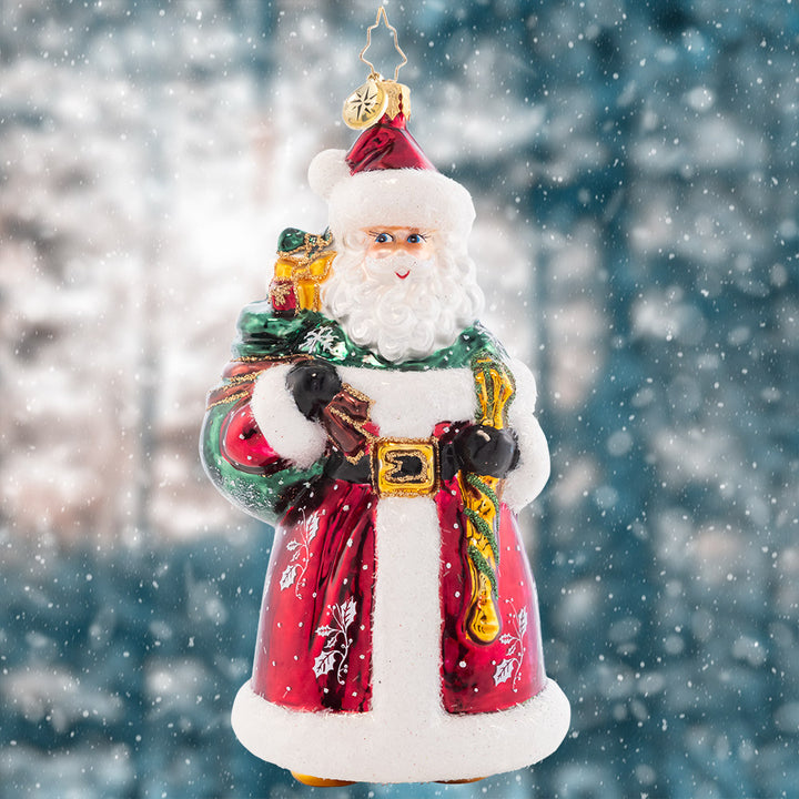 Ornament Description - Brant's Brilliant Santa: In a traditional red robe speckled with snowflakes and holly, this Santa is just like his designer, Brant Moll- Keeping it classic, but with a hint of flair!