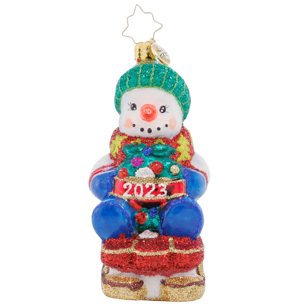 Ornament Description - Sliding Through the Year: This little snowman is riding his toboggan sled into the Christmas season, looking forward to more winter fun before the holidays are all done!