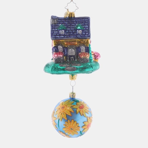 Video - Ornament Description - Countryside Cottage: A vibrant flower-adorned blue round accompanies this colorful and happy-looking house. Welcome home holiday memories with this joyful piece!