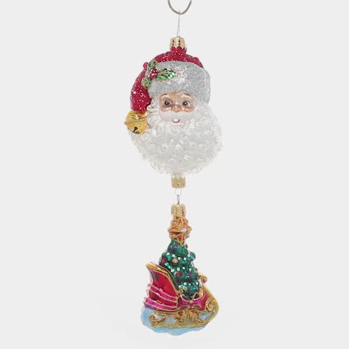 Video - Ornament Description - Santa's Magic Sleigh: If you're looking for the perfect piece to add a unique twist to traditional Christmas imagery, this is the one! An ornate sleigh ornament, carrying a fully trimmed Christmas tree dangles from a larger ornament of Santa's smiling face. This video shows the ornament spinning slowly. 