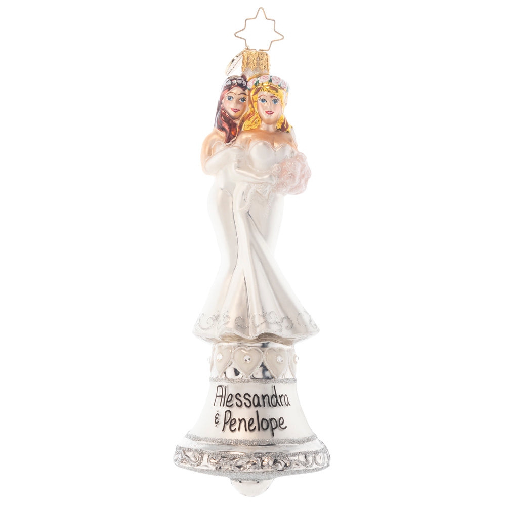 Ornament Description - Passionately Perfect: This lovely couple stands together atop a silver bell, ready to ring in the start of their new relationship! Don't they look beautiful in their matching wedding dresses? Note: Please allow approximately one month (on top of shipping time) for our elves to personalize your ornament.