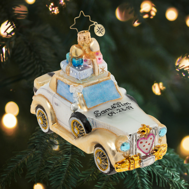 Ornament Description - Wedding Bliss Chariot: The happy couple takes off after their wedding in this wedding bliss chariot! Their gifts stacked high atop the roof and their bags packed for a honeymoon of memories at the back, this loving couple is ready for their happily ever after! Note: Please allow approximately one week (on top of shipping time) for our elves to personalize your ornament.