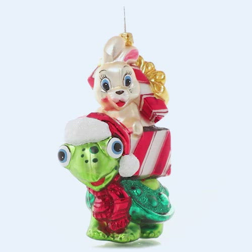 Ornament Description - Race to The Finish:You know what they say…slow and steady wins the race! A tortoise and a hare team up for some Christmas time fun, racing to deliver gifts to their destinations! This video shows the ornament spinning slowly.