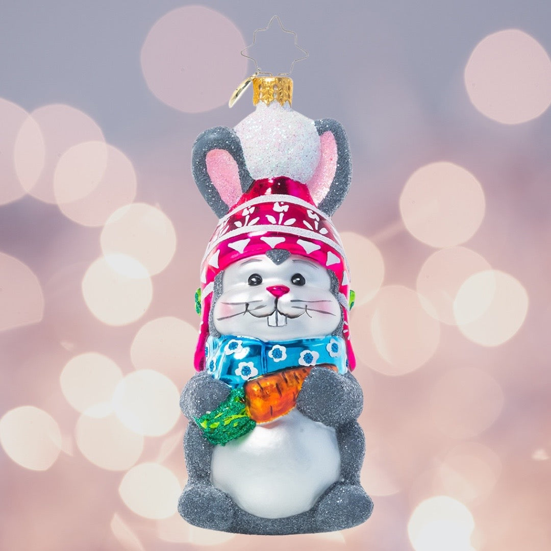Ornament Description - Bundled Up Bunny: This little cotton tail looks ready to hit the slopes with his snow hat and a bag full of provisions from the garden. All he needs now are some skis!